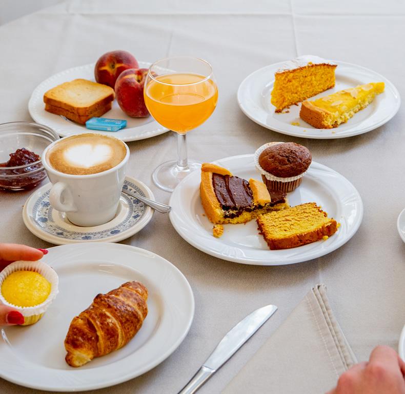 Colazione con dolci, croissant, caffè, succo d'arancia e frutta.