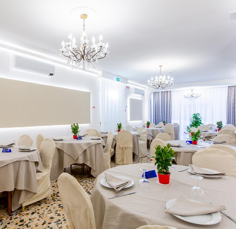 Elegante sala da pranzo con tavoli apparecchiati e lampadari a soffitto.