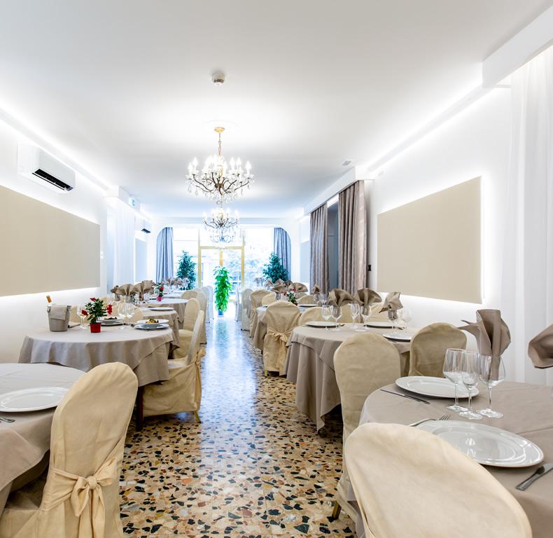 Elegante ristorante con decorazioni raffinate e tavoli apparecchiati, illuminato da lampadari a soffitto.